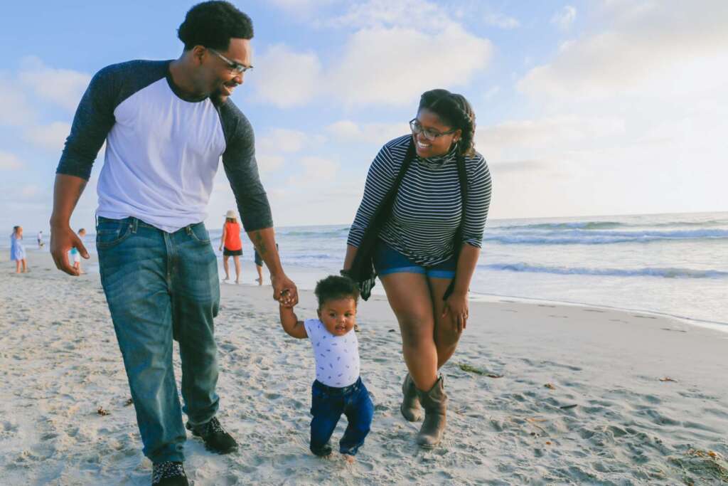 Heat wave temperatures; mom and dad walk with baby on the beach