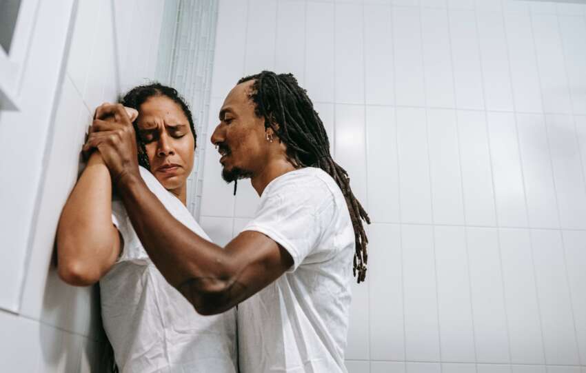 aggressive ethnic man and frightened woman quarreling in bathroom