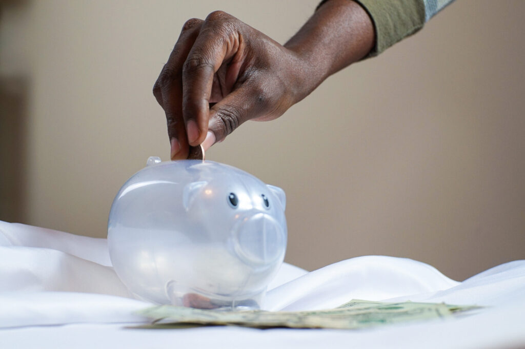 get good with money; ; hand putting money in a piggy bank
