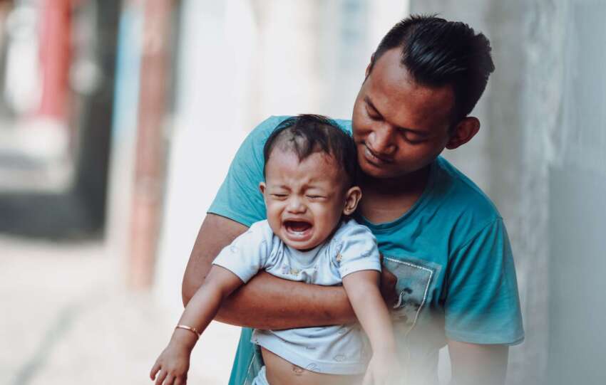 Man holding crying baby; public meltdowns