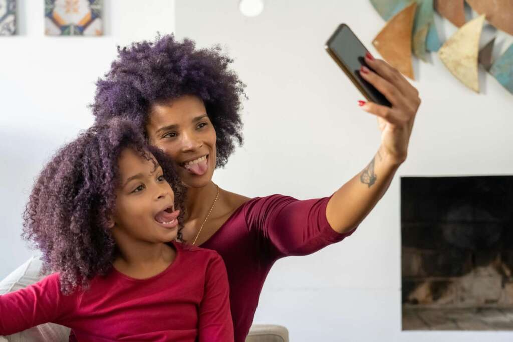 Mother and Daughter Taking a Selfie and Sticking Their Tongues Out. Article on Sharenting Statistics