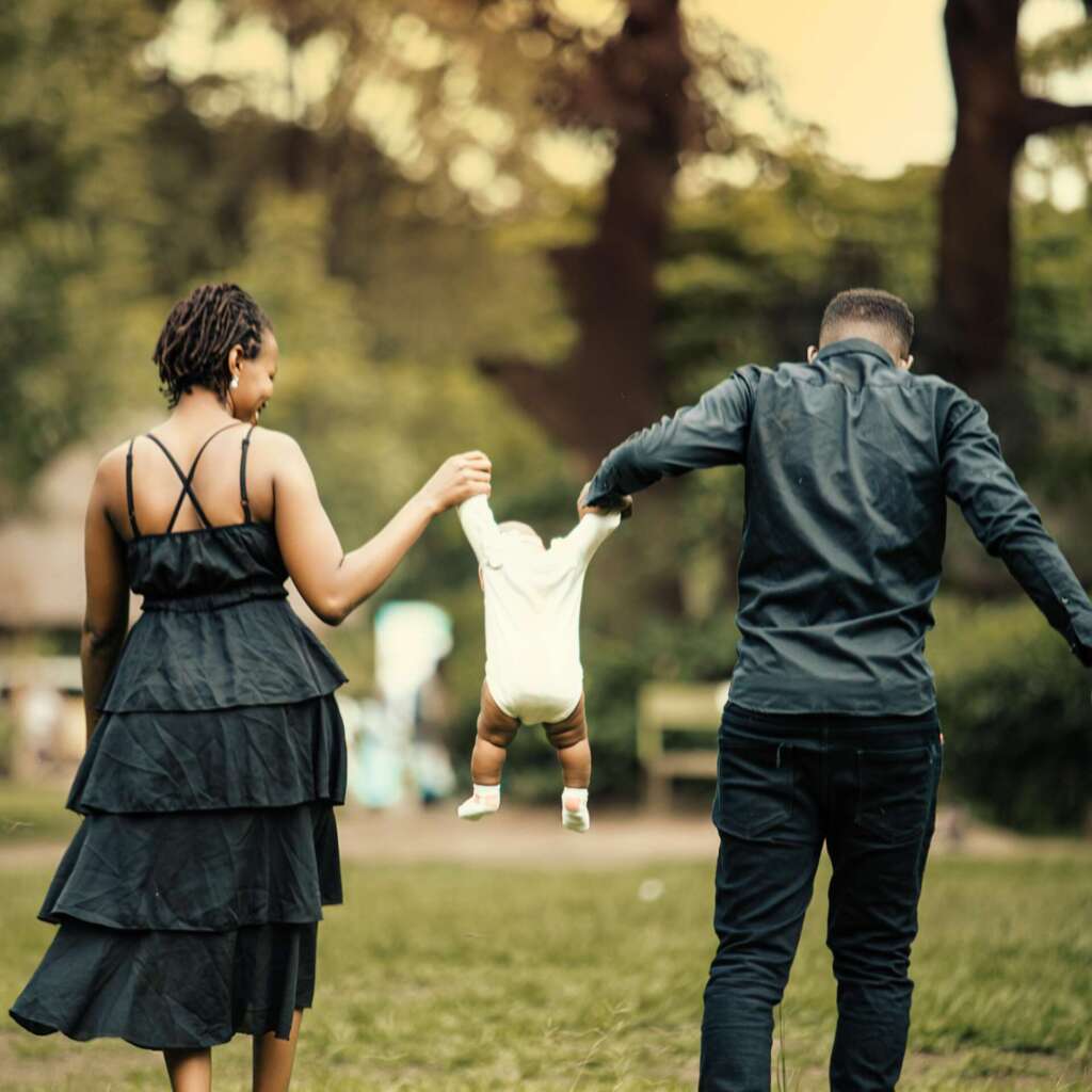 Happy family strolling in lush park setting; co-parenting in the digital age
